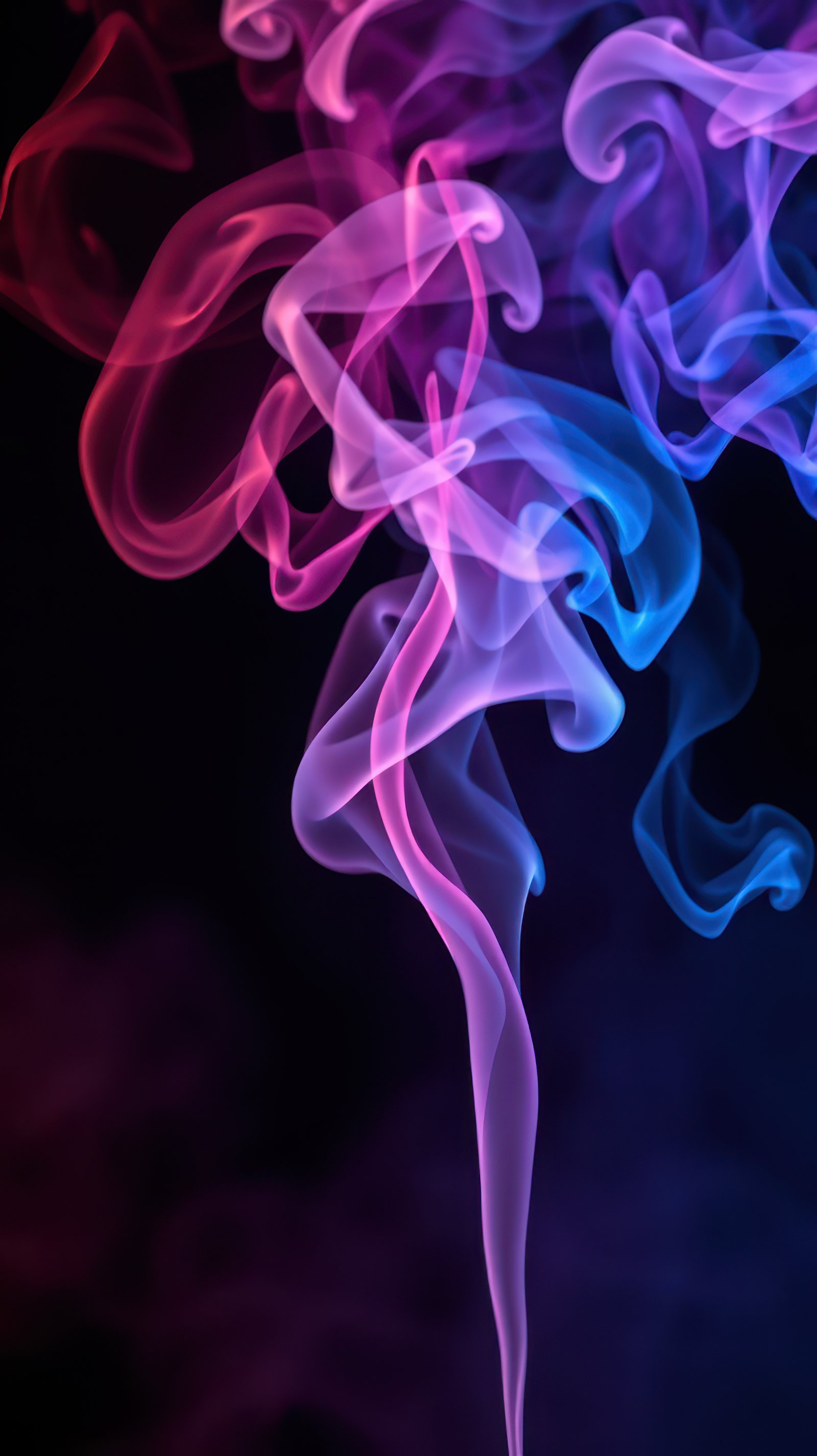 Colorful swirling smoke in shades of pink and blue creating a mesmerizing effect against a dark background